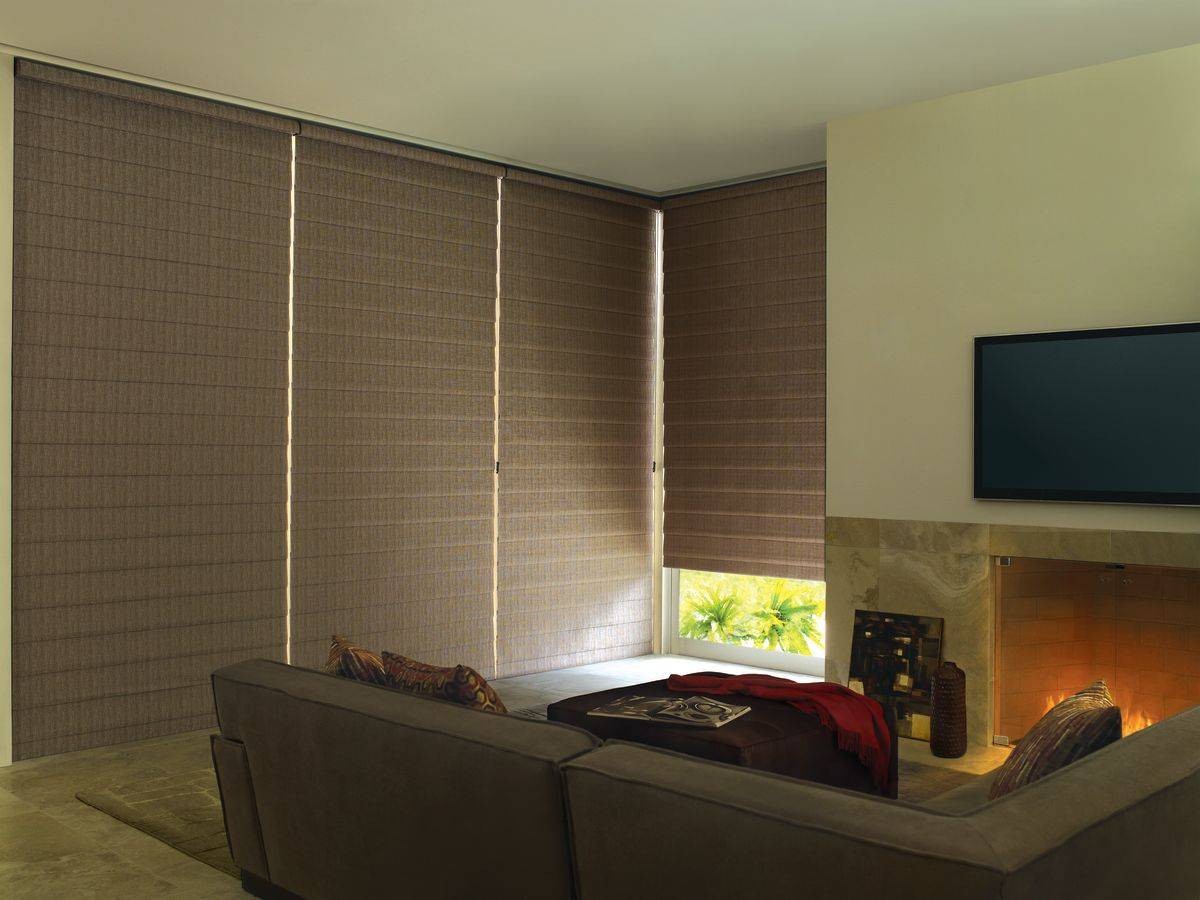 Brown Hunter Douglas Alustra® Woven Textures® Roman Shades blocking light in a family living room near Miami, FL