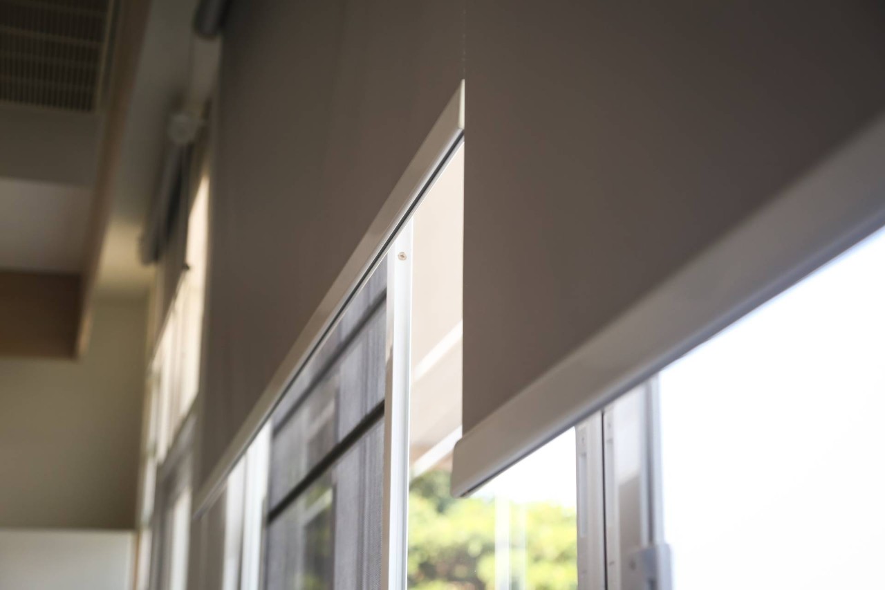 Beige motorized blackout shades on a bedroom window, opening in the morning at Fine Shadings & Décor near Miami, FL